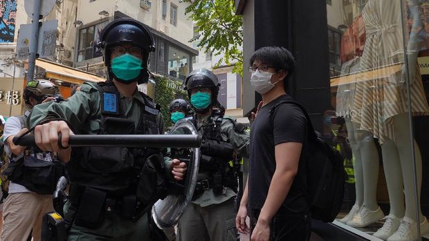 Riot police standing guard as a woman tries to cross the street in the Central district of Hong Kong, Wednesday, May 27, 2020. Hong Kong police massed outside the legislature complex Wednesday, ahead of debate on a bill that would criminalize abuse of the Chinese national anthem in the semi-autonomous city. (AP Photo/Vincent Yu)