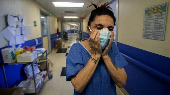 Nurse Cristina Settembrese fixes two masks to her face during her work shift in the COVID-19 ward at the San Paolo hospital in Milan, Italy, April 10, 2020. Settembrese spends her days caring for COVID-19 patients in a hospital ward, and when she goes home, her personal isolation begins by her own choice. (AP Photo/Luca Bruno)