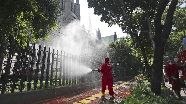 Seorang petugas pemadam kebakaran menyemprotkan desinfektan dalam upaya membantu menghentikan penyebaran wabah koronavirus baru di luar katedral di Jakarta. AP/Achmad Ibrahim