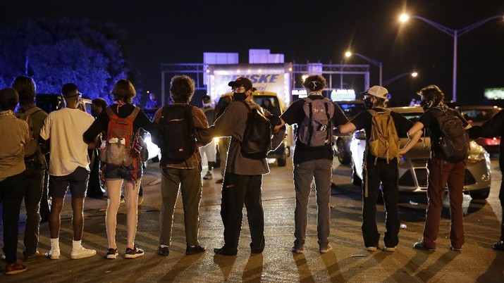 A person is covered with liquid after being officials deployed teargas at protesters Saturday, June 13, 2020, near the Atlanta Wendy's where Rayshard Brooks was shot and killed by police Friday evening following a struggle in the restaurant's drive-thru line in Atlanta. (AP Photo/Brynn Anderson)