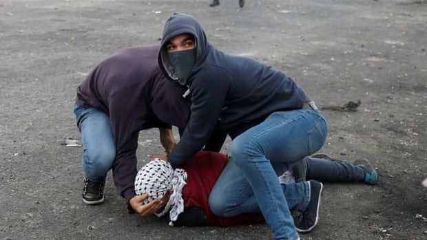 Dua Musta'ribeen membengkuk seorang pengunjuk rasa Palestina