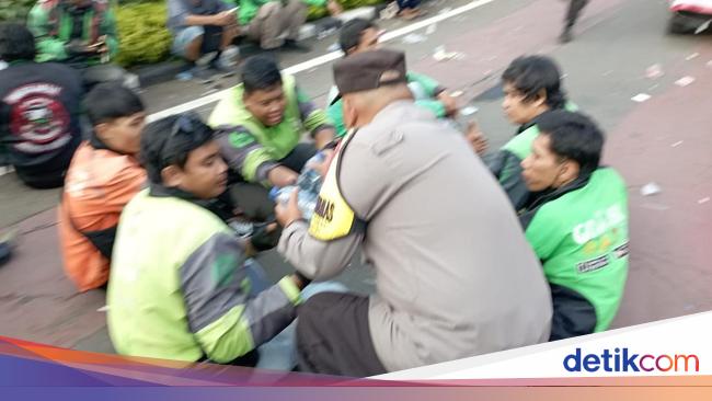 Aksi Humanis Polisi Bagi-bagi Minuman ke Massa Demo Ojol di Patung Kuda