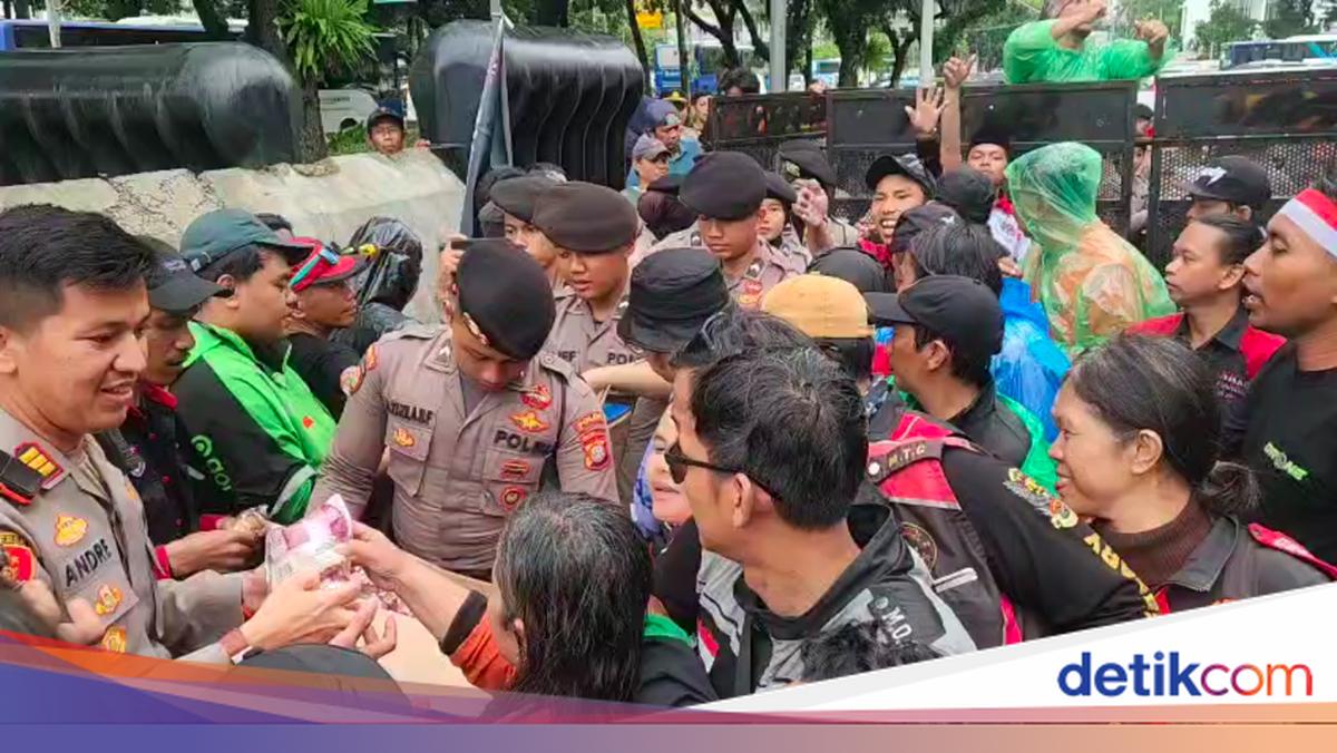 Anggota Polda Metro Bagikan Makan-Minum ke Massa Demo di Silang Monas