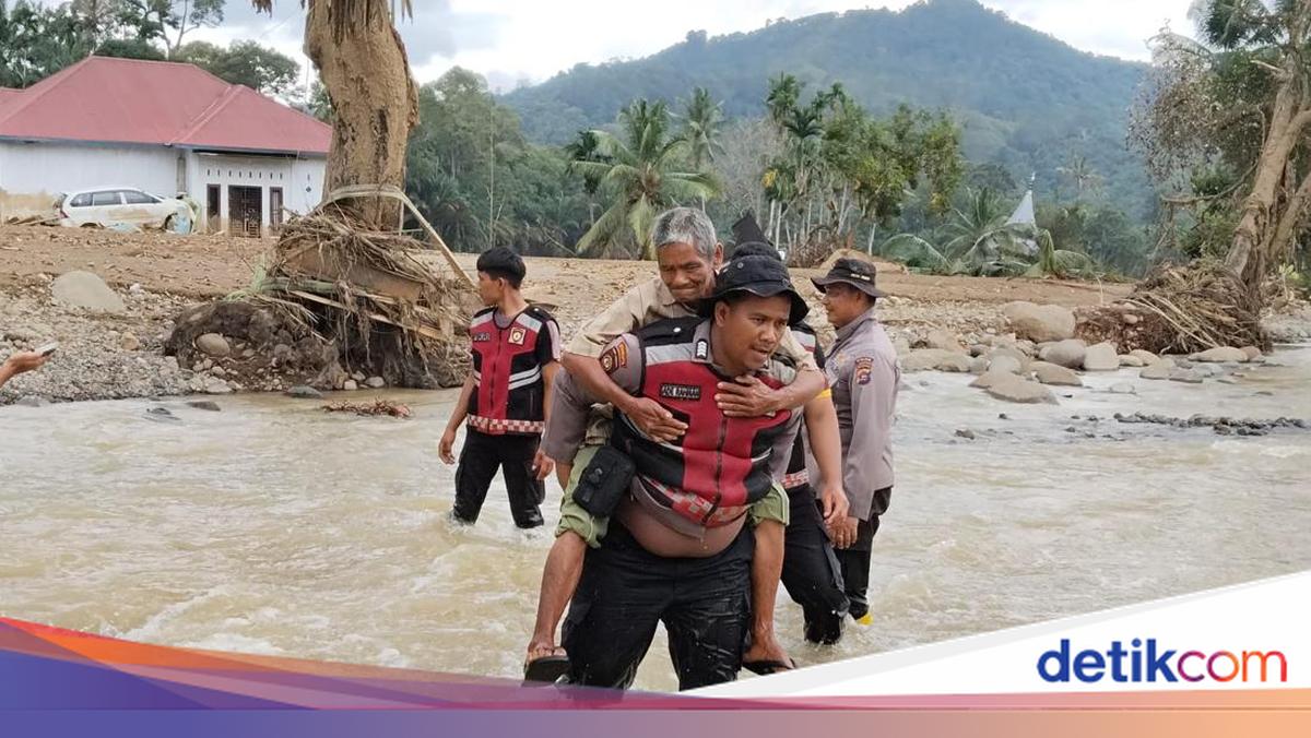 Jembatan Darurat Putus, Polisi Gendong Lansia Seberangi Sungai di Agam