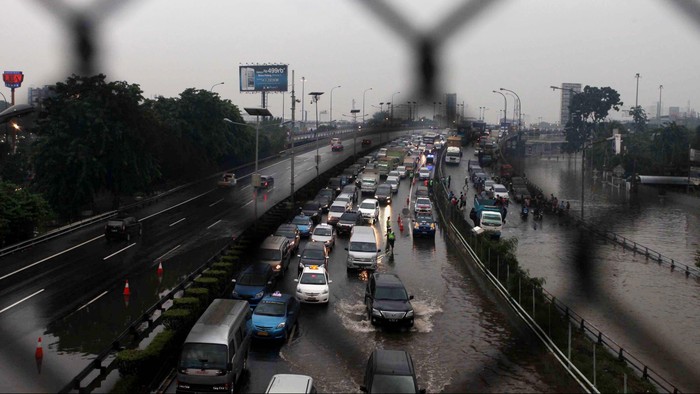 Warga berusaha melintasi genangan banjir yang melanda ruas jalan tol Pluit-Tomang, Jakarta, Kamis (17/1). Akibat banjir yang merendam ruas tol menyebabkan kemacetan dan ruas jalan sulit dilalui. File/detikFoto.