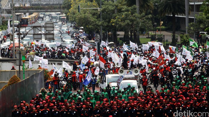 Demo buruh membuat lalu lintas dari Bundaran HI arah Istana Merdeka, Jl Medan Merdeka Utara, terhambat. Kendaraan tak bisa melintas dan harus mengalah tertahan di belakang barisan buruh yang menuntut kenaikan UMP ini.