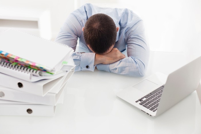 pria tidur di meja kantor