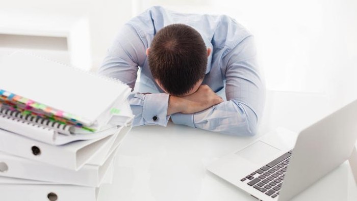 pria tidur di meja kantor