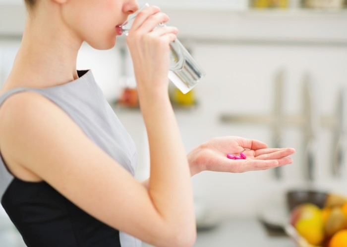 Minum vitamin Ilustrasi seorang wanita yang sedang mengonsumsi vitamin atau suplemen