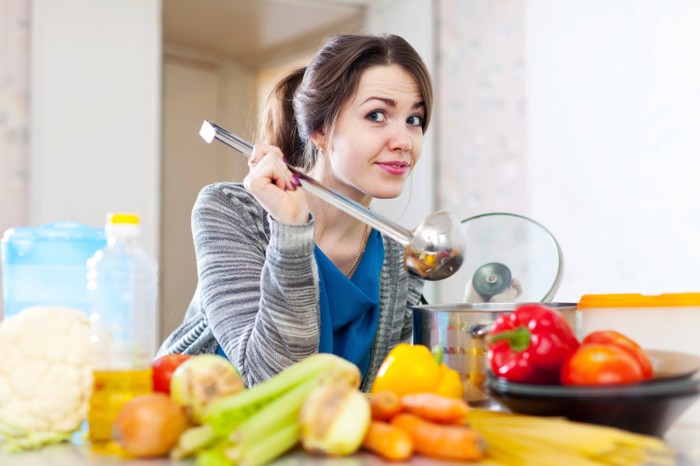 Ilustasi seorang wanita yang sedang memasak sayur di dapurnya