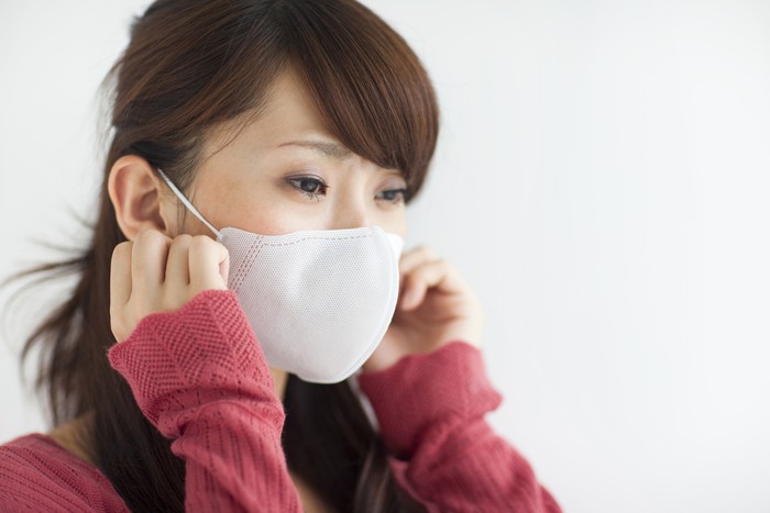 ilustrasi masker Seorang perempuan mengenakan masker putih.