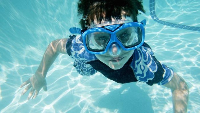 Ilustrasi seorang anak sedang berenang menggunakan kacamata khusus
