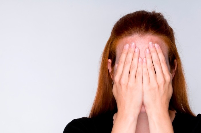 Woman covering face with hands.