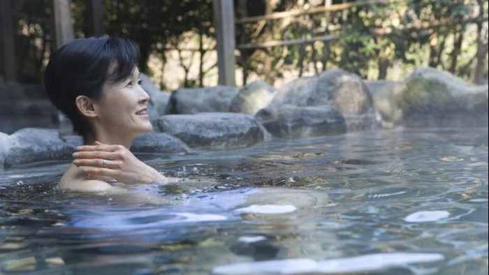 Ilustrasi seorang wanita yang sedang mandi berendam di kolam air panas