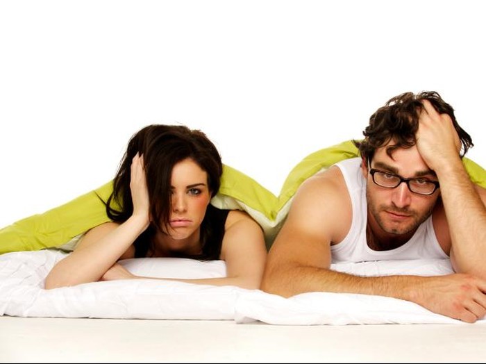Pasangan di tempat tidur Portrait of an upset woman sitting on a bed while her fiance is sleeping