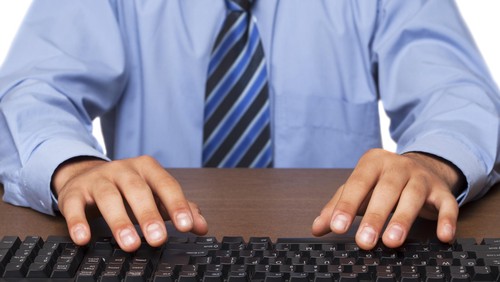 Seorang pria berpakaian biru sedang mengetik.