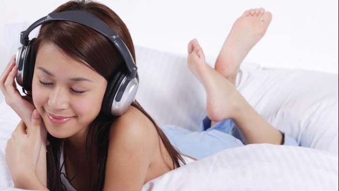 Wanita muda sedang mendengarkan musik.