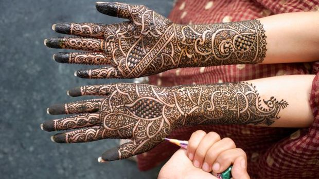 Ilustrasi tangan yang sedang dipakaikan tato temporer/henna