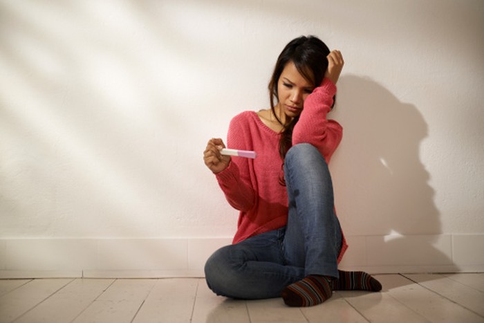 Ilustrasi tes kehamilan young woman with pregnancy test kit