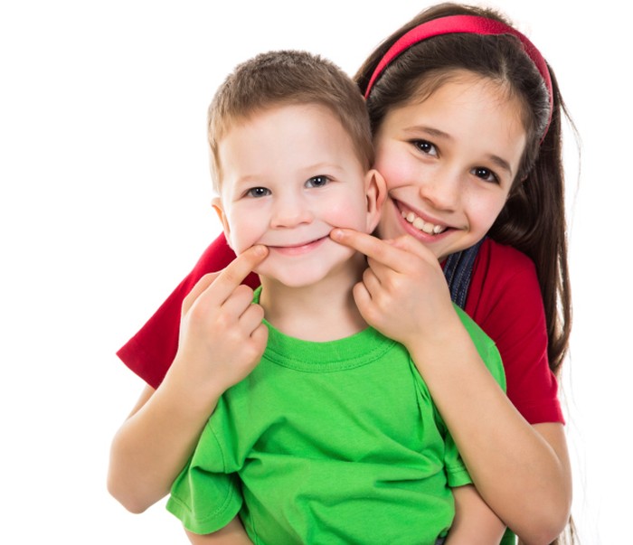 Dua anak sedang tersenyum bahagia.