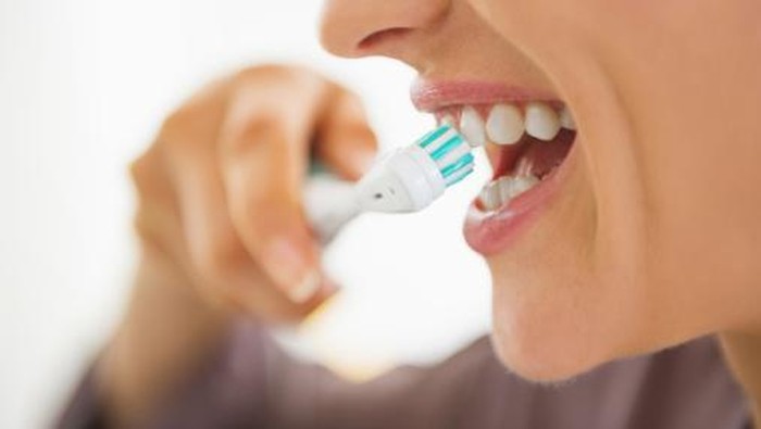 closeup on happy young woman brushing teeth