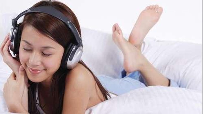 Wanita muda sedang mendengarkan musik.