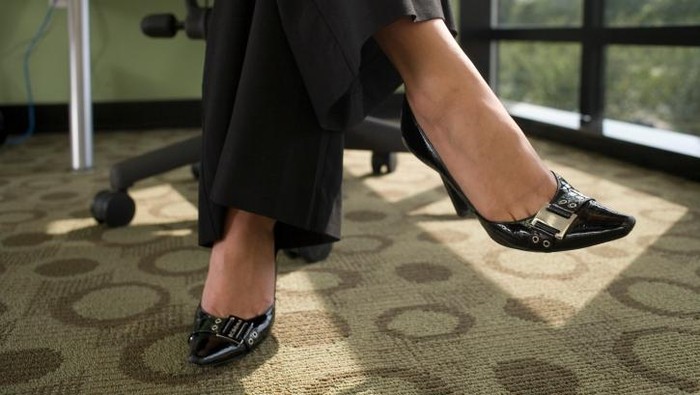 Perempuan sedang duduk di kursi, hanya tampak kaki bagian bawahnya.