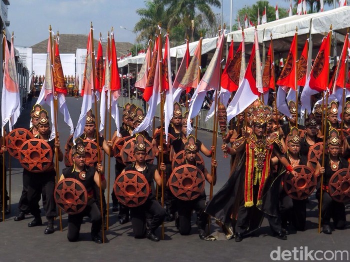 Ajang Jember Fashion Carnaval (JFC) tak hanya menjadi parade kota, namun juga karnaval yang mendapat perhatian dunia saat ini. Di tahun ke-14 nya, JFC pun tampil semarak dengan ribuan kostum megah dan berparade sepanjang 3,6 km. ema kejayaan kerajaan Majapahit membuka parade JFC tahun ini yang lebih dramatis. Puluhan orang berdandan ssbagai pengawal kerajaan, sementara anggota keluarga kerajaan memakai kostum yang lebih megah. Kapolres Jember, Sabilul Alif bahkan ikut tampil sebagai patih di cerita Majapahit. Sementara presiden JFC, Dynand Fariz menjadi karakter Hayam Wuruk dengan kereta emasnya. Alissa Safiera/detikcom.
