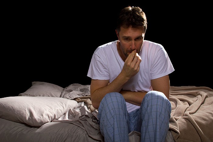 Frightened Woman in Bed with the Sheets Pulled Up to her Face