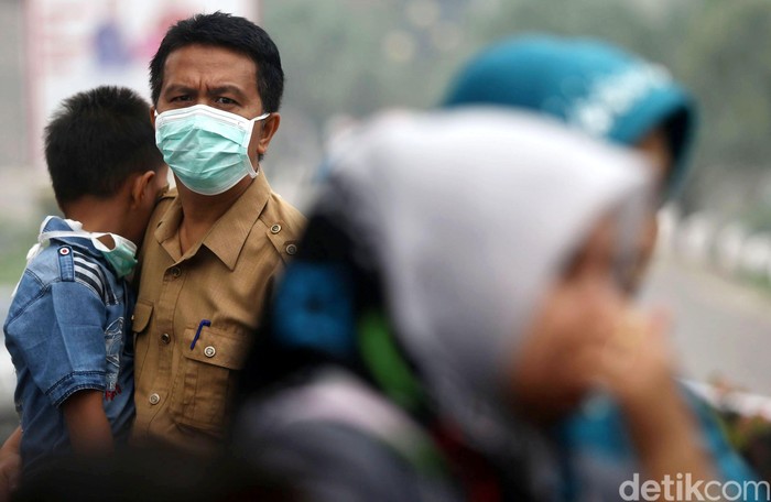 Warga Padang, Sumatera Barat, beraktifitas di  tengah kepulan kabut asap, Kamis (08/10/2015). Masih diselimutinya kawasan sekitaran padang membuat sejumlah warga harus mengenakan masker saat beraktivitas. Grandyos Zafna/detikcom.