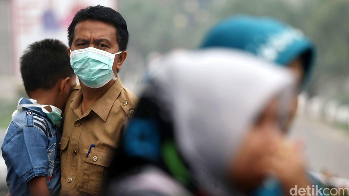 Warga Padang, Sumatera Barat, beraktifitas di  tengah kepulan kabut asap, Kamis (08/10/2015). Masih diselimutinya kawasan sekitaran padang membuat sejumlah warga harus mengenakan masker saat beraktivitas. Grandyos Zafna/detikcom.