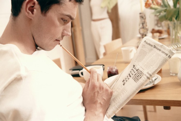 MAN STUDYING CROSSWORD AT TABLE