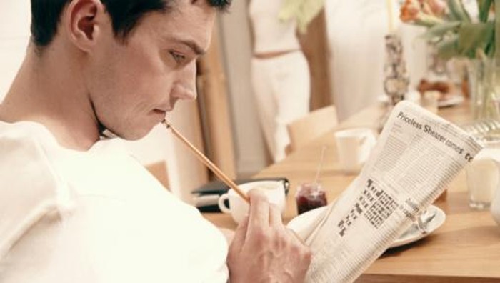 MAN STUDYING CROSSWORD AT TABLE