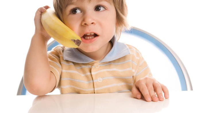 Anak kecil pura-pura menelepon menggunakan pisang