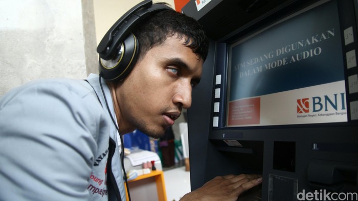Menteri Sosial Khofifah Indar Parawangsa berbincang dengan nasabah disabilitas yang didampingi saat mencoba bertransaksi di ATM Mandiri khusus bagi penyandang cacat di kantor Kementerian Sosial Jakarta, Selasa (1/12/2015). Peluncuran ATM untuk para disabilitas oleh Kemensos dalam rangka memperingati Hari Disabilitas yang jatuh tanggal 3 Desember 2015. Bank Mandiri, Bank BCA, BRI dan BNI saat ini telah mengembangkan layanan ATM disabilitas untuk membantu penyandang cacat dalam melakukan transaksi perbankan. Layanan ini juga sebagai realisasi dari kesepahaman yang telah ditandatangani Menteri Sosial, Gubernur Bank Indonesia dan perbankan. Agung Pambudhy/Detikcom.