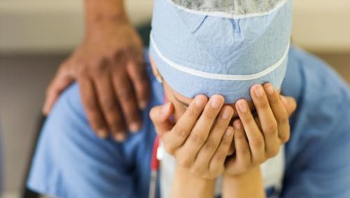 Asian surgeon sitting with head in hands
