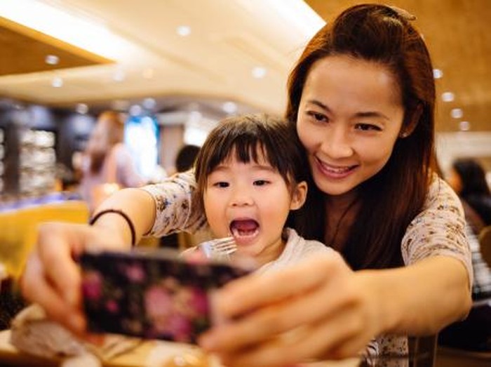 ilustrasi ibu dan anak Mom & toddler girl taking selfie joyfully in cafe