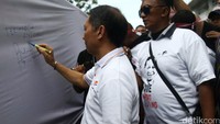 Ia juga sempat membubuhkan tanda tangan di kain putih yang dibawa demonstran.