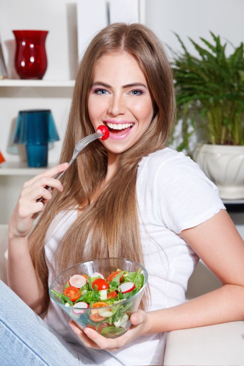 young woman eating fruit salad in bedroom