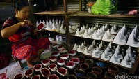 Seorang pekerja sedang mengisi cetakan candi dengan bahan fiber.