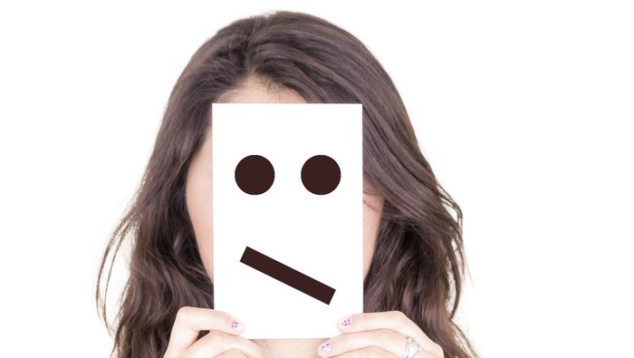 woman with emoticon on a paper in her face