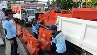 Petugas memasang pembatas jalan.