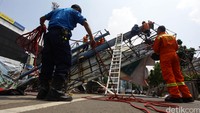 Seorang petugas menyiapkan tali yang akan digunakan untuk mengevakuasi baliho.