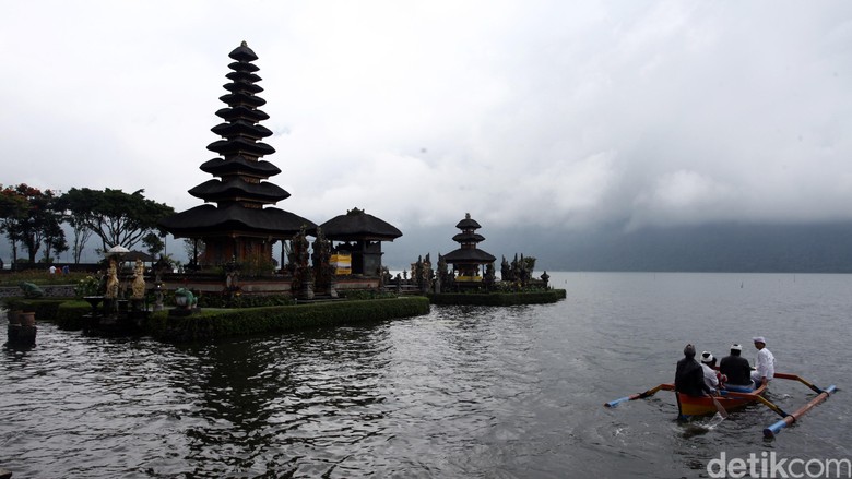Warga bersiap melakukan larung sesaji di Danau Bratan, Bedugul, Bali dengan latar belakang Pura Ulun Danu.