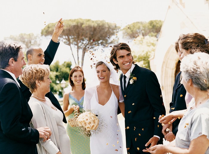 Pernikahan People Throwing Confetti Over a Newlywed Couple Leaving Church