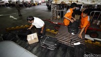 Petugas memindahkan barang ke troli.