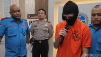 Ia mengenakan baju tahanan dan penutup wajah.