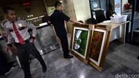 Seorang petugas bersiap memindahkan dua lukisan tersebut.
