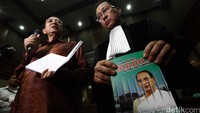 Suryadharma memberikan keterangan pers. Sementara kuasa hukumnya menunjukkan buku berjudul Penyelenggara Haji Diadili Politisasi Atau Islamophobia.