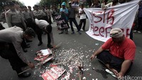 Polisi membersihkan berbagai atribut demo yang dibakar massa.